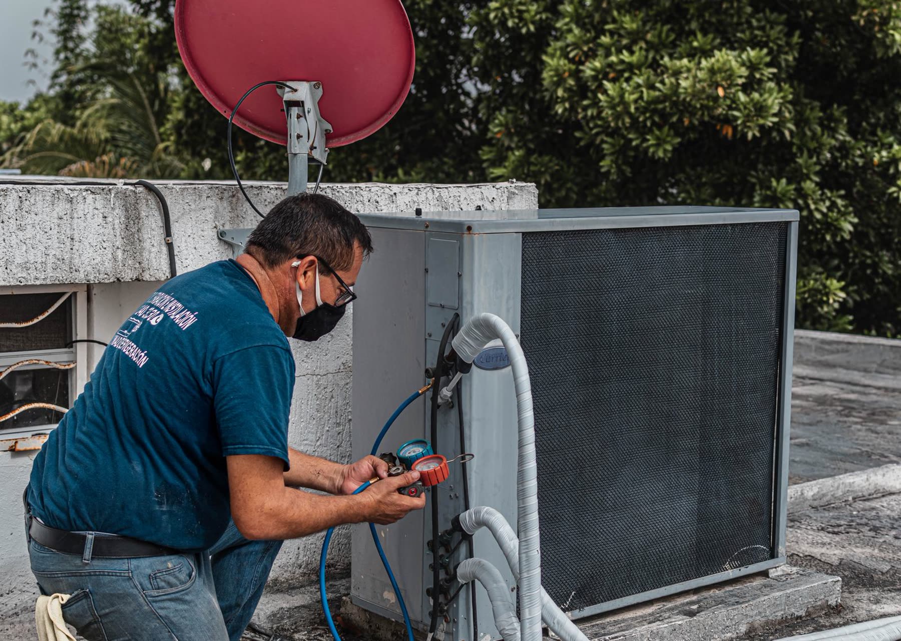 An HVAC technician working on an outdoor air conditioning unit